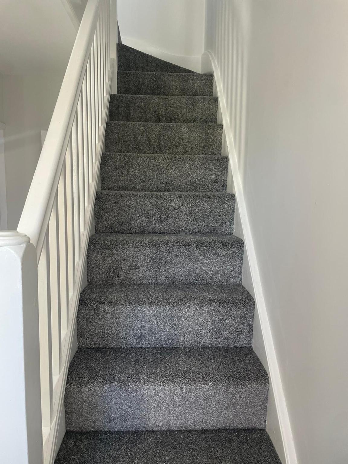 Grey carpet fitted to a staircase, each tread and riser cut tight to the strings and nosings