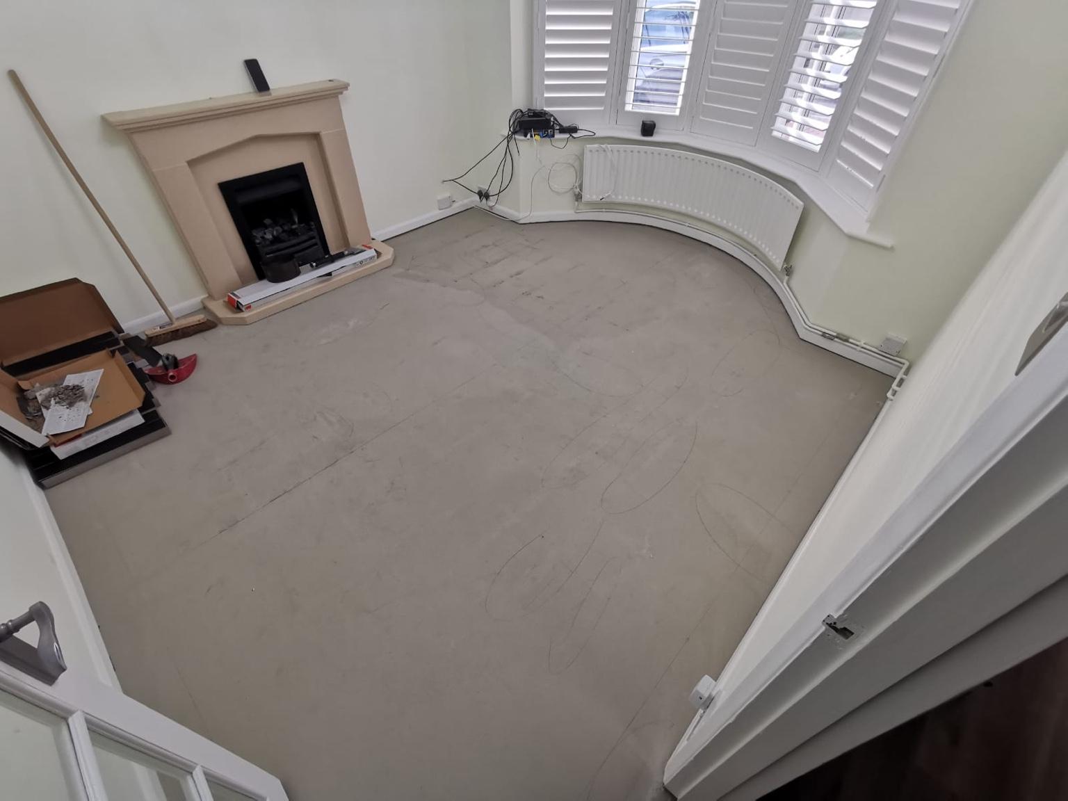 The living room before fitting: the subfloor prepared and swept, with the curved bay window, curved radiator and fireplace in view