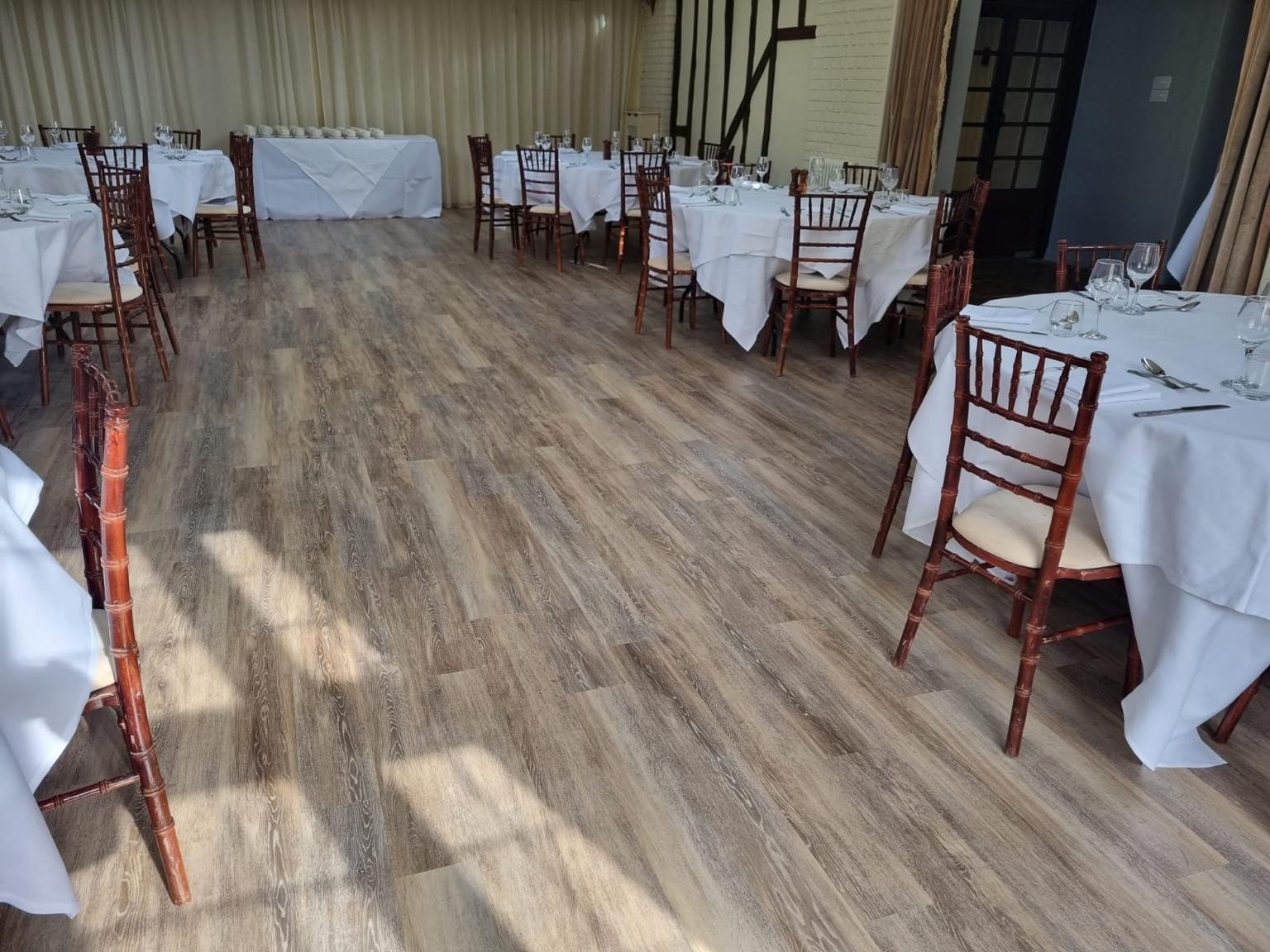 Wood-effect plank flooring fitted throughout a function room, laid out with tables set for dining