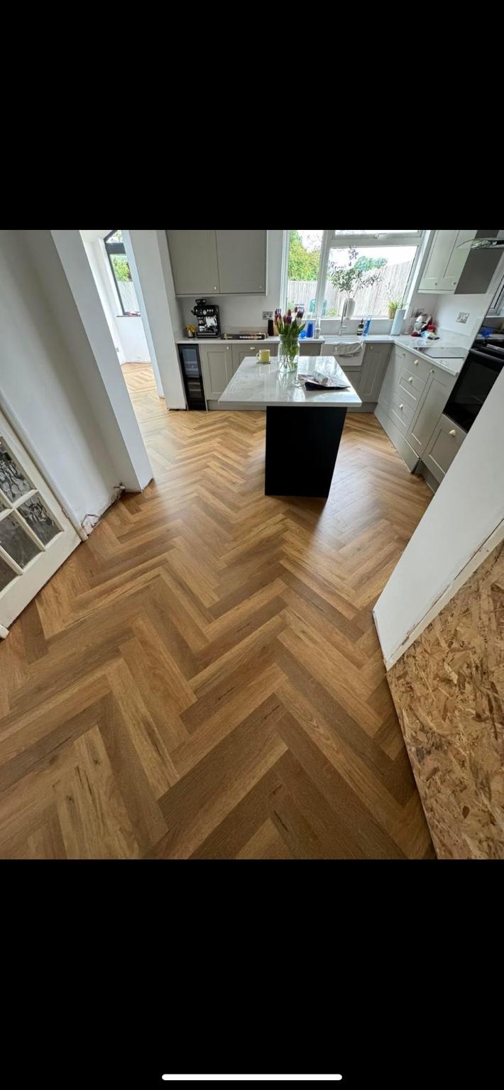 Herringbone flooring fitted through a kitchen, running around the island unit and on into the room beyond