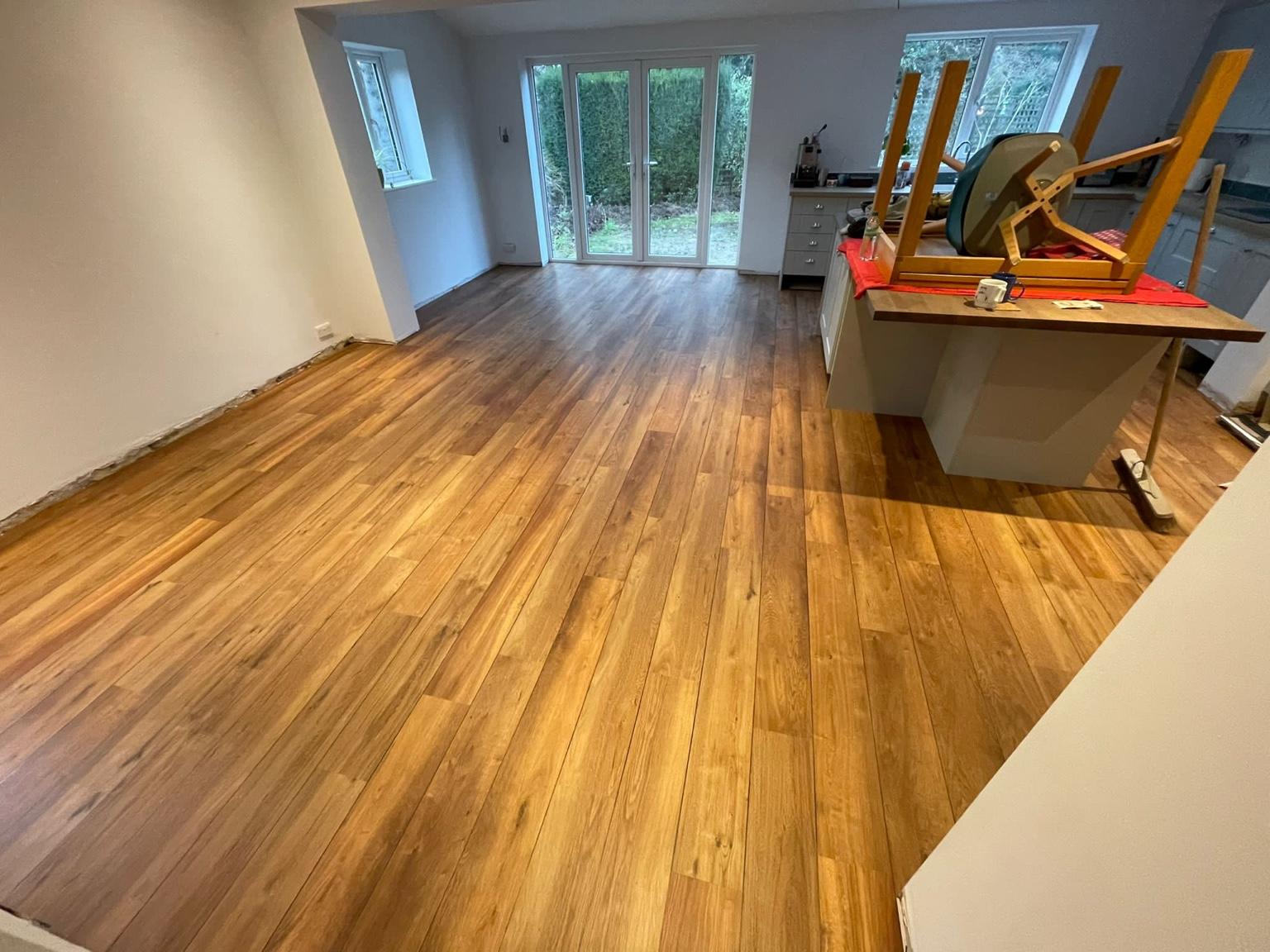 Plank flooring fitted through an open-plan kitchen and dining room, running up to French doors onto the garden